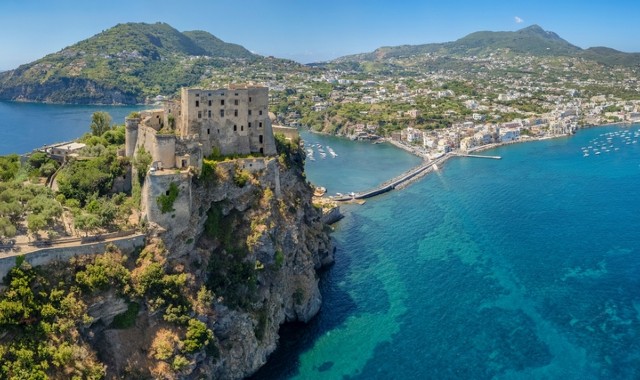 Aerial view of Aragonese Castle on Ischia island facing town and blue sea