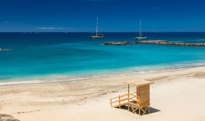 Playa del Duque beach in Tenerife, Spain, featuring a lifeguard tower and sailing boats