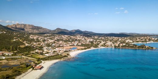 Vista aerea della spiaggia di Pittulongu, a Olbia, con sabbia bianca e montagne all'orizzonte