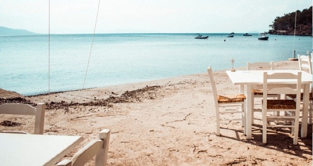 Tavern tables and chairs on a beach in Aegina